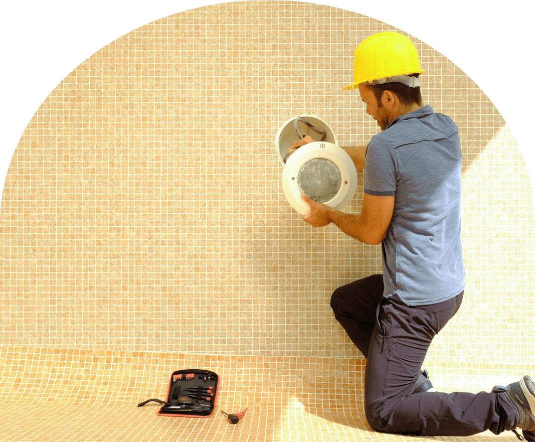 Worker in safety helmet inspecting a pipe indoors.